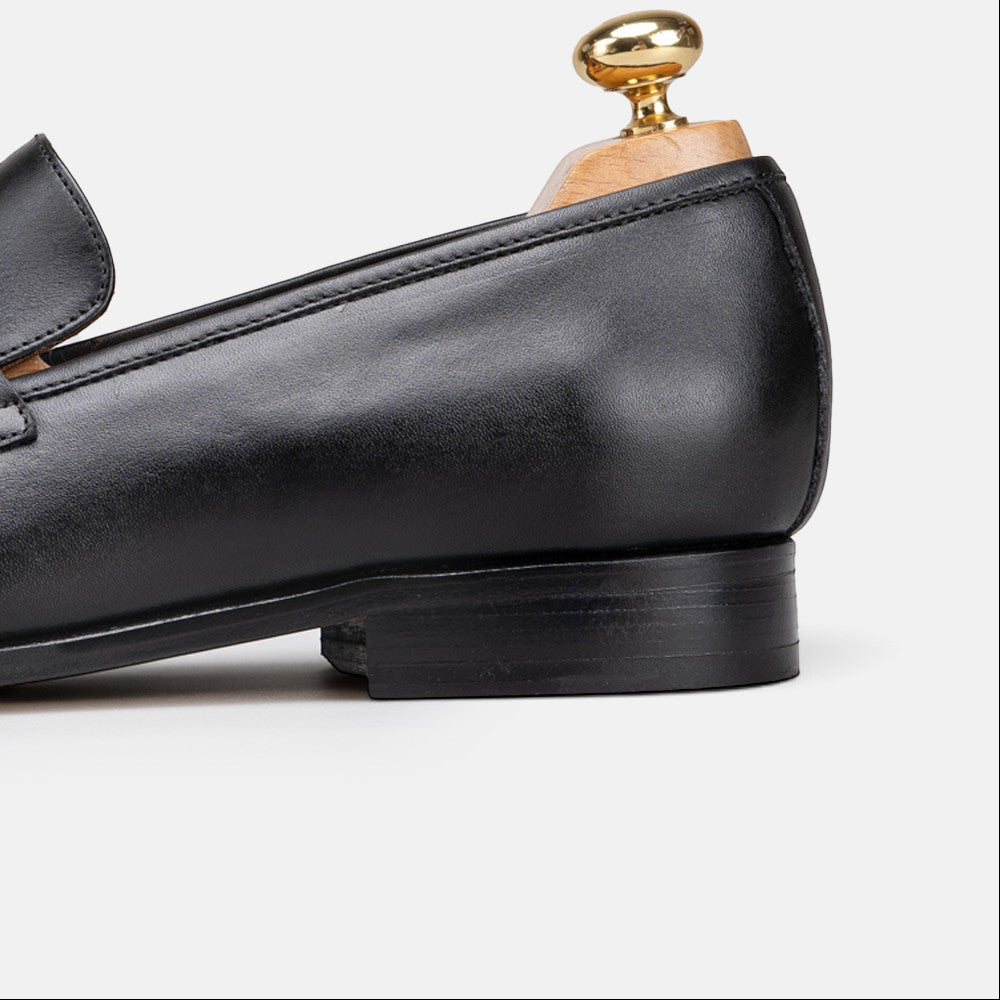VOLZAK black leather loafer with a stacked heel and wooden shoe tree insert, side profile view.