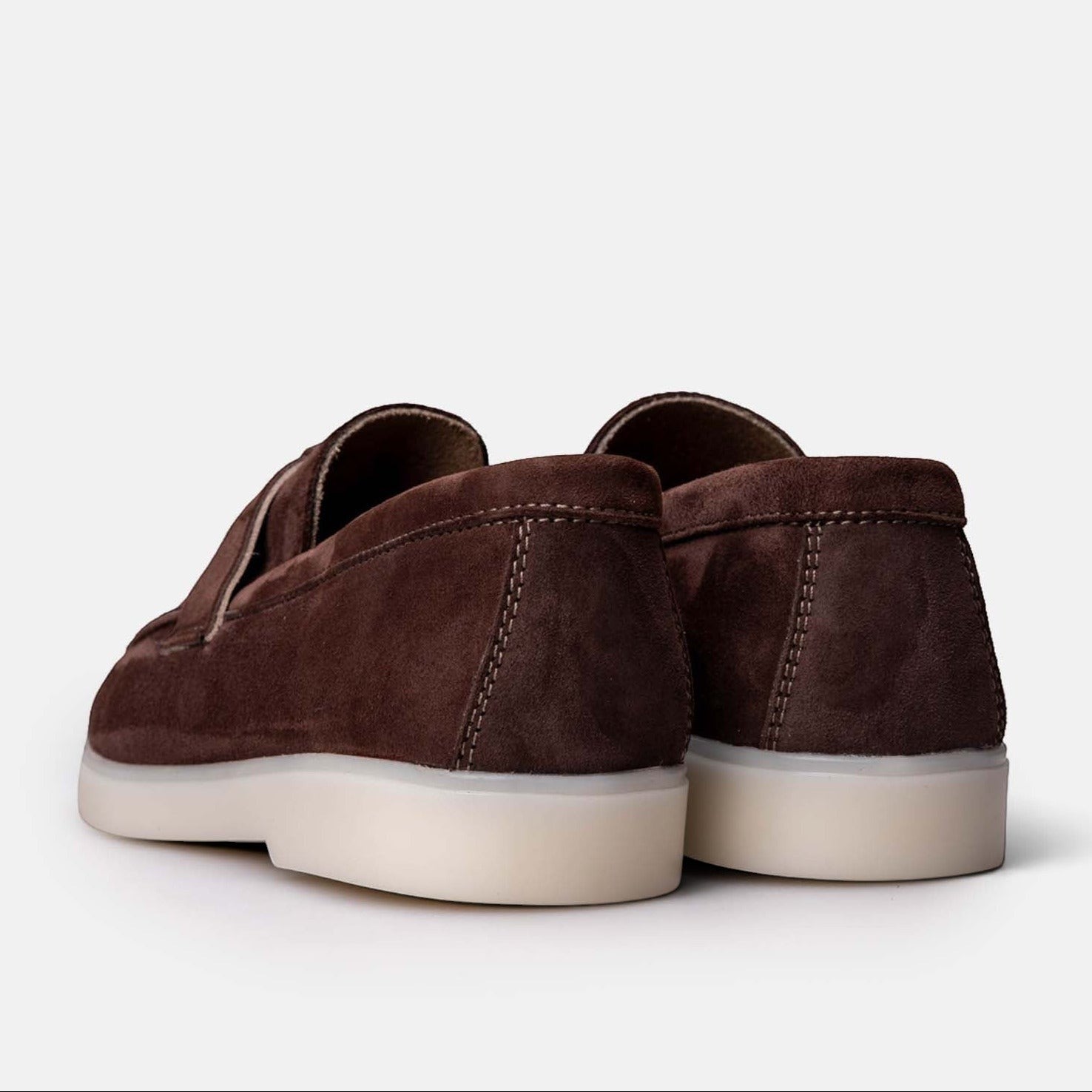 Rear view of VOLZAK brown suede moccasins with a white rubber sole