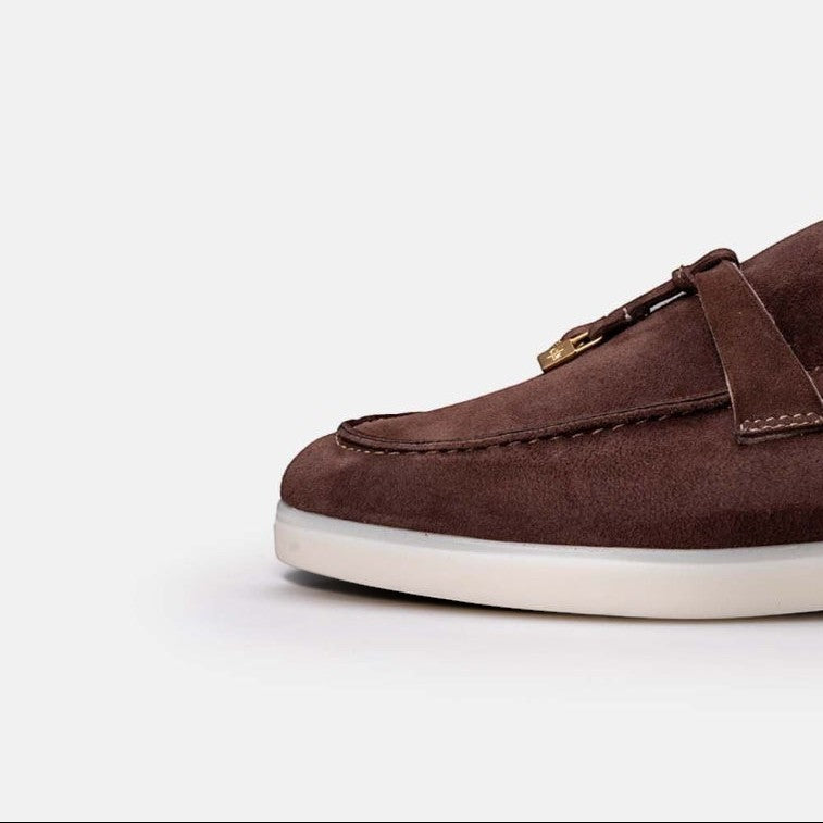 VOLZAK brown suede moccasin with a white rubber sole and decorative tassel detail, close-up view.