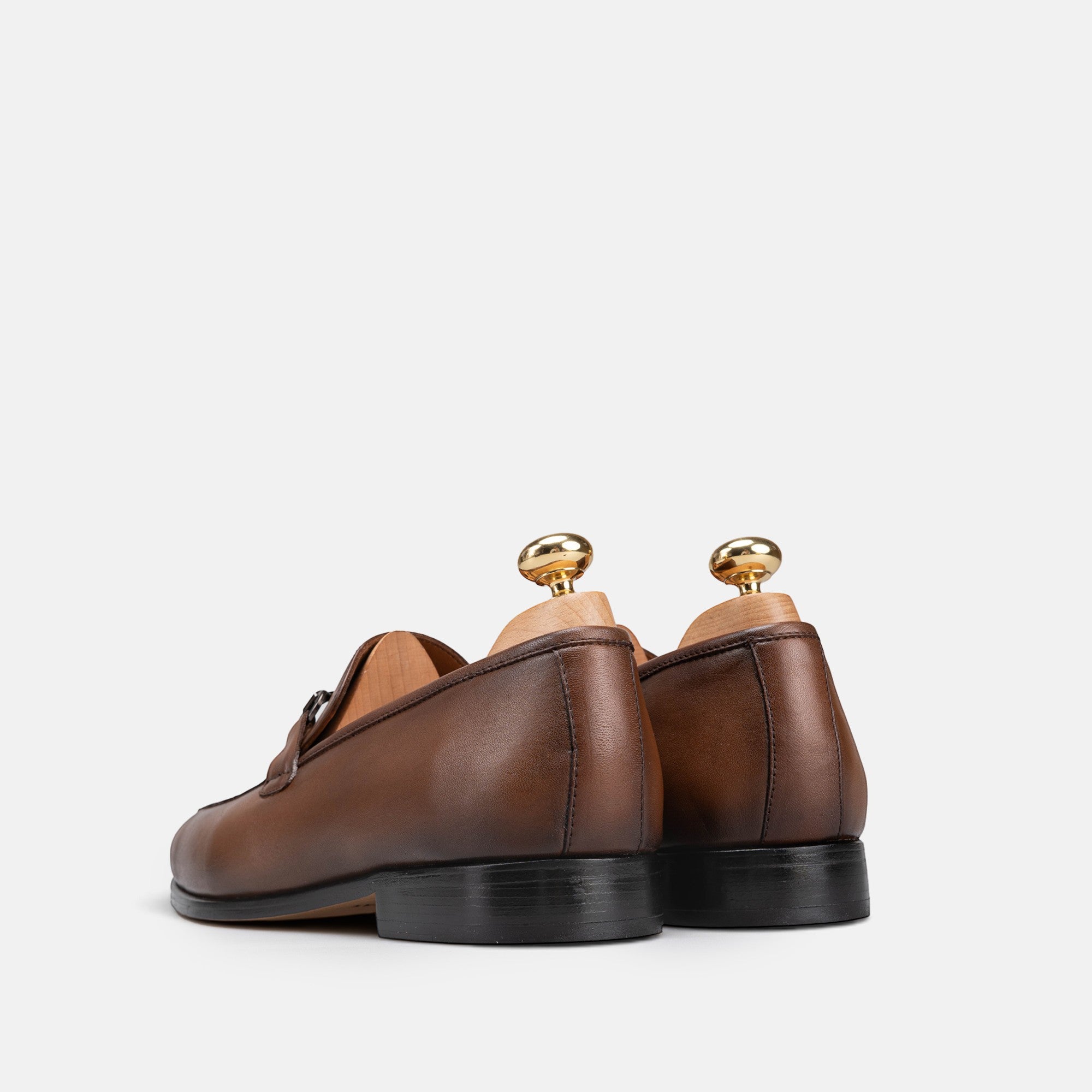Rear view of VOLZAK vintage brown leather loafers with wooden shoe trees on a white background