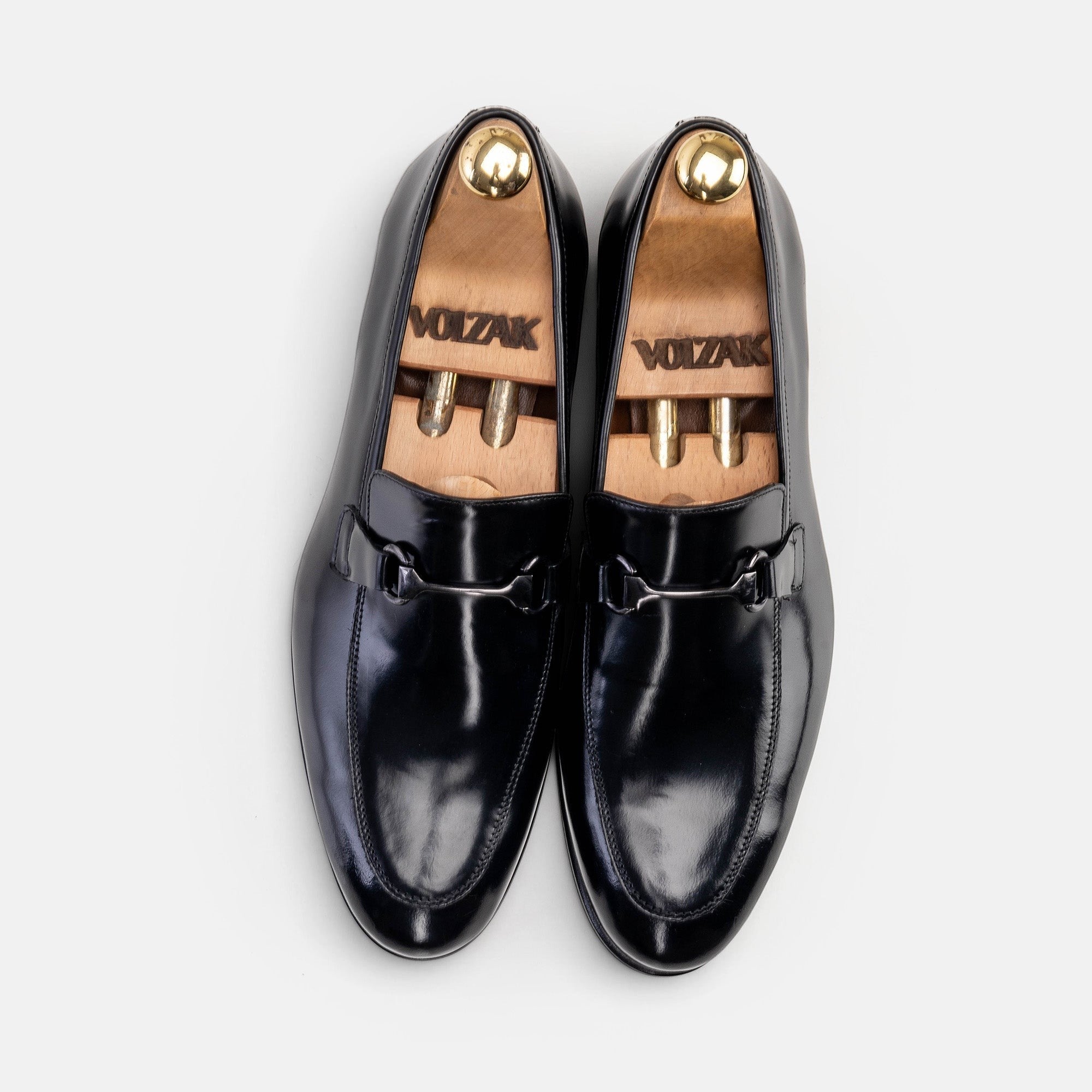 VOLZAK black leather loafers with a polished finish and metal bit detail, shown from a top-down view.