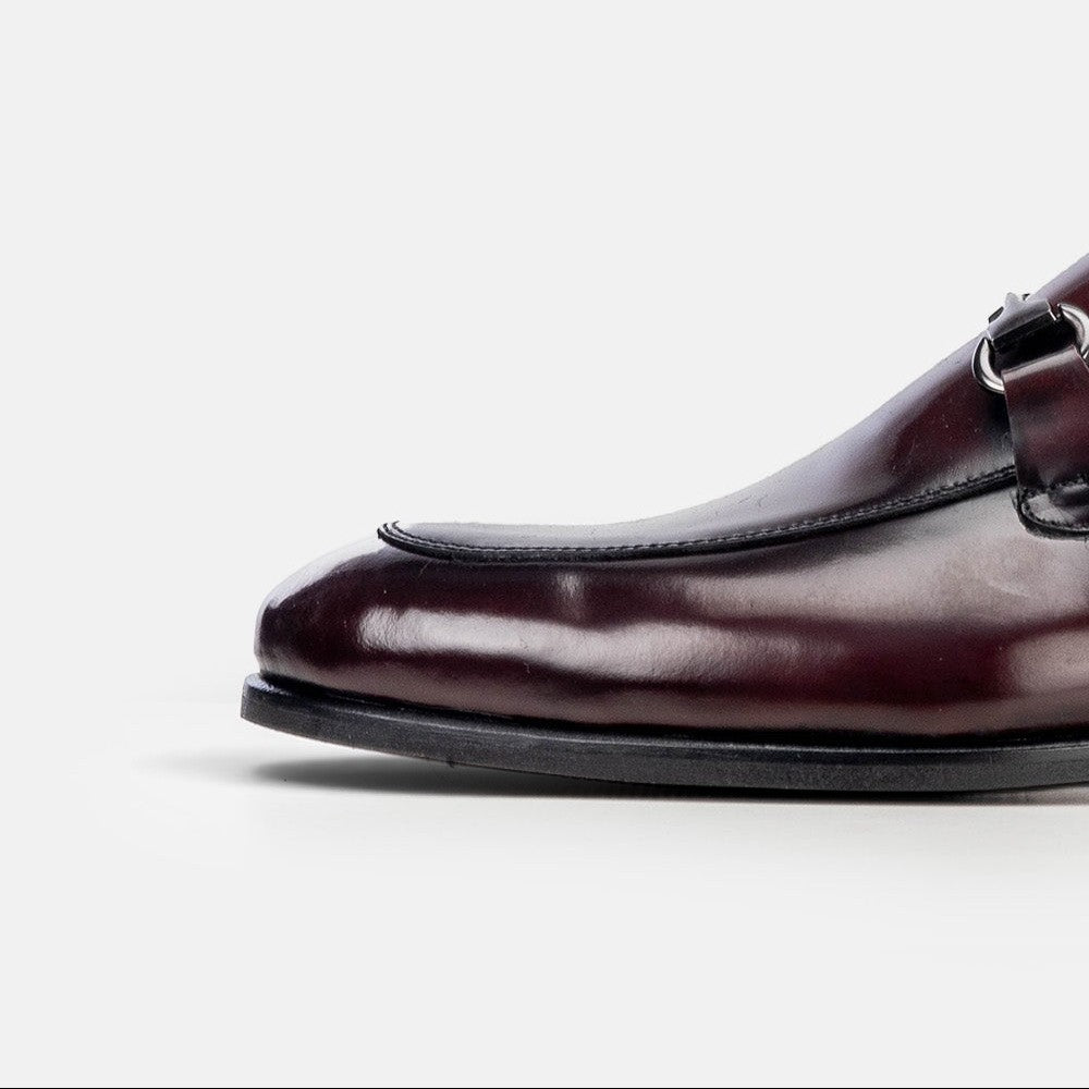 VOLZAK bordeaux leather loafer with a silver metal buckle detail, showing a polished finish and apron toe design.