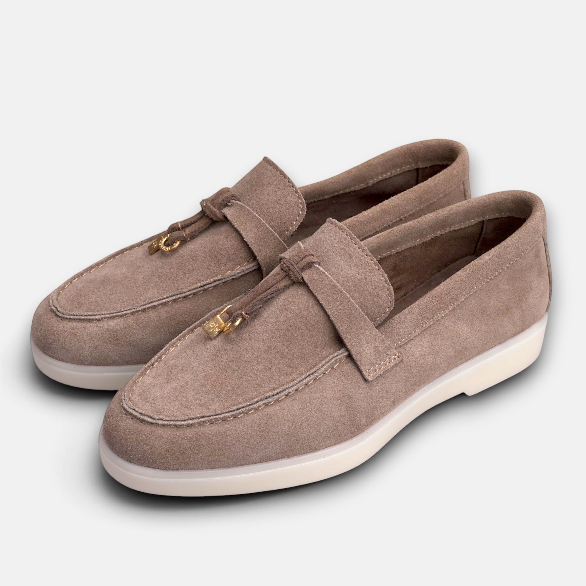 VOLZAK taupe suede moccasins with leather lining, rubber sole, and decorative gold-toned metal tassel detail.