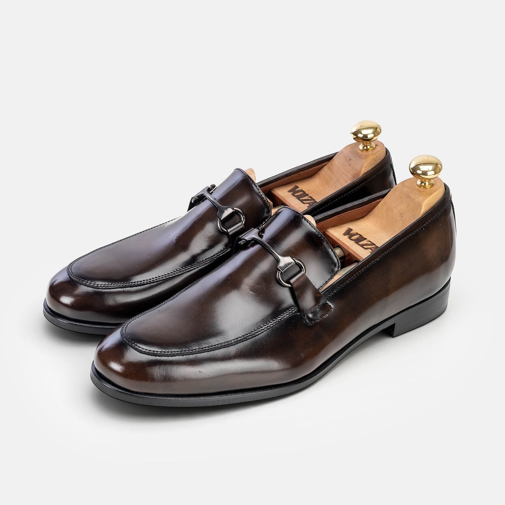 VOLZAK vintage brown leather loafers with a metal bit detail and wooden shoe trees on a white background